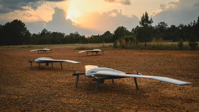 Vier drones staan op open veld in bosrijke omgeving.