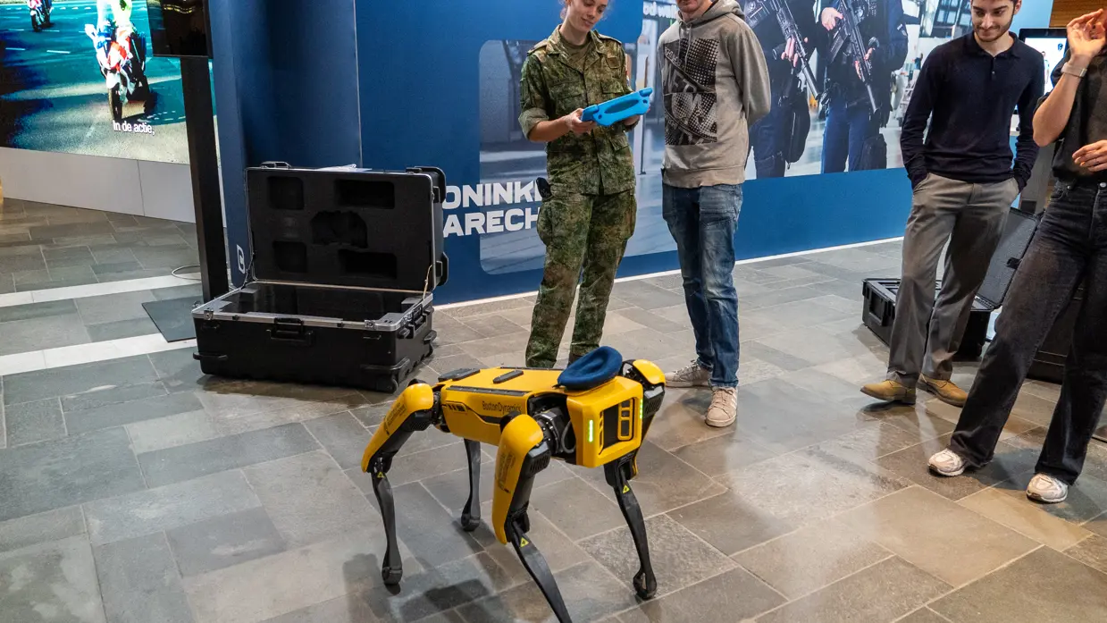 Bezoekers kijken naar een robothond. 