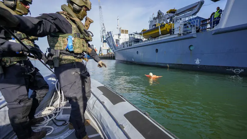 Twee rubberboten kruisen elkaar op het water voor de kade.