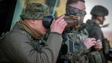 Een Nederlandse militair tuurt door een kijker. 