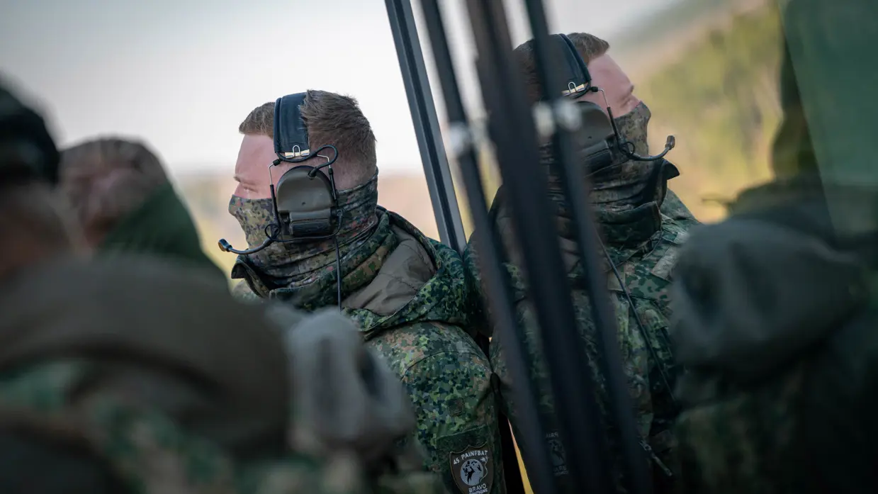 Twee militairen staan klaar, aan de rechterkant is hun reflectie in een oppervlakte te zien.