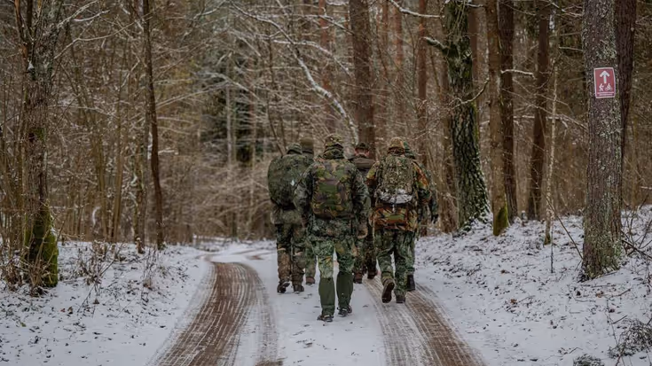 Soldaten lopen in de sneeuw door het bos.