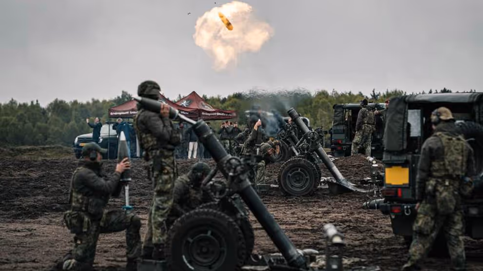 Een rookwolk in de lucht en enkele 120mm mortieren en militairen er omheen.