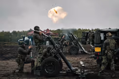 Een rookwolk in de lucht en enkele 120mm mortieren en militairen er omheen.