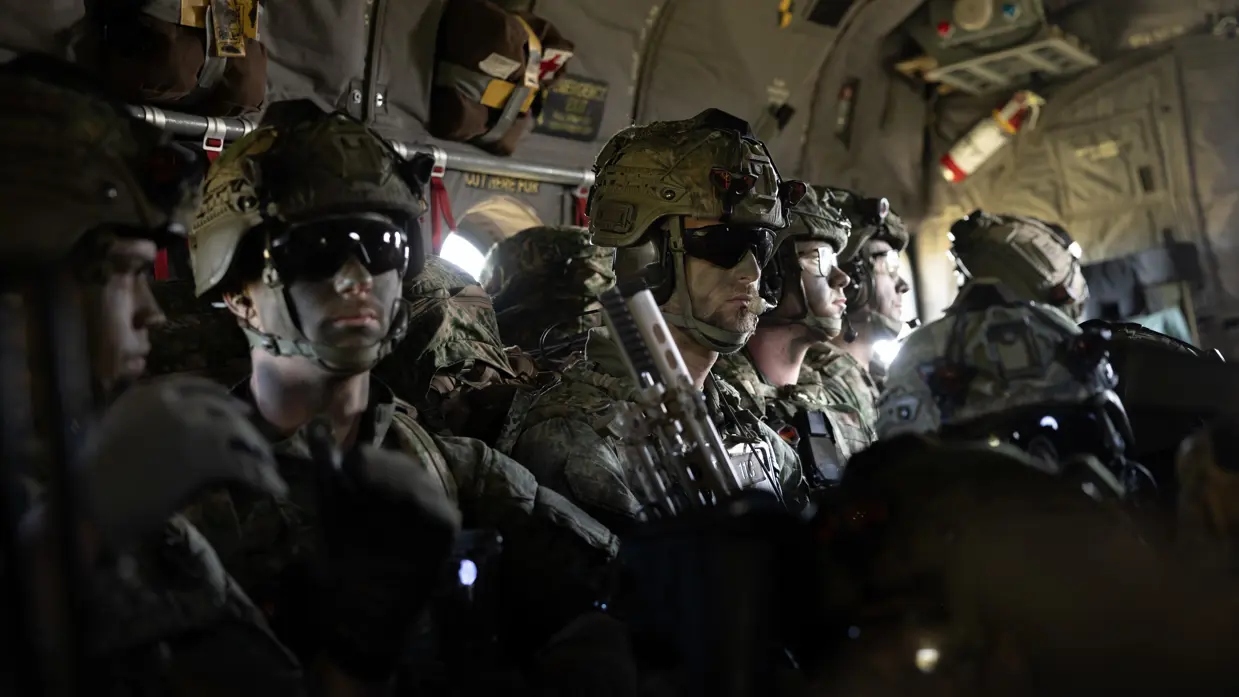 Parachutisten zitten met volledige gevechtsuitrusting in een C-130 Hercules tijdens de vlucht naar de dropzone voor een airborne-operatie.