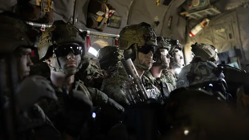 Parachutisten zitten met volledige gevechtsuitrusting in een C-130 Hercules tijdens de vlucht naar de dropzone voor een airborne-operatie.