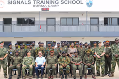 Groepsfoto van Nederlandse trainers en lokale militairen voor een trainingslocatie. 