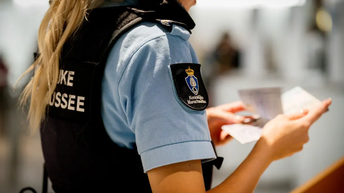 Een marechaussee controleert een document.