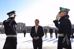 Staatssecretaris Tuinman staat tussen 2 saluerende Zuid-Koreaanse militairen. 