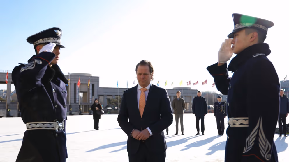 Staatssecretaris Tuinman staat tussen 2 saluerende Zuid-Koreaanse militairen. 
