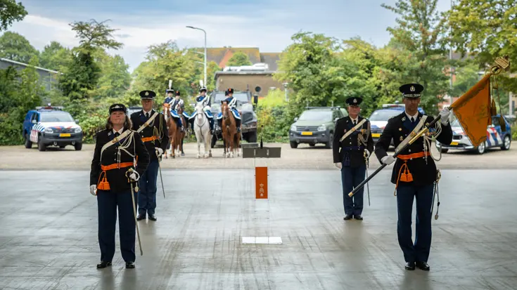De vertrekkend commandant en de nieuwe staan opgesteld. Luitenant-generaal Costongs staat rechts en heeft de officiële standaard van de Marechaussee vast.