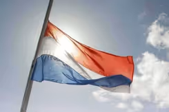 Nederlandse vlag wappert halfstok. 