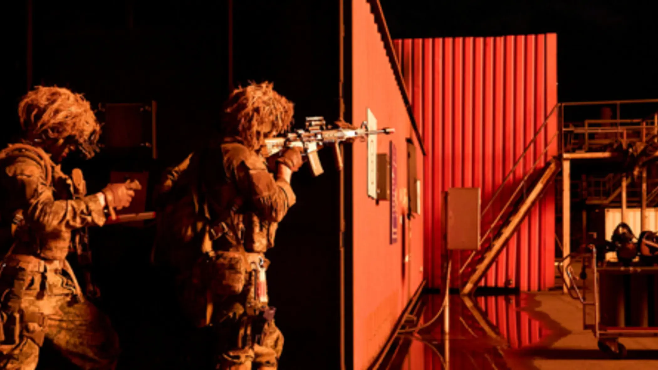 Mariniers bewegen zich langs een container bij nacht en richten hun wapens.