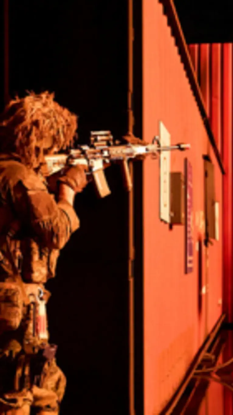Mariniers bewegen zich langs een container bij nacht en richten hun wapens.