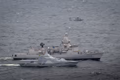 Een Zweedse schip met daarachter de Van Amstel en daarboven een NH90-helikopter.