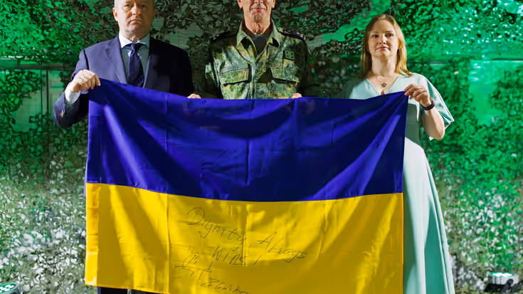 Drie personen houden een Oekraiense vlag vast.