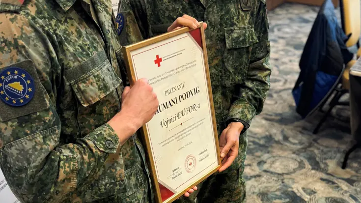Twee militairen houden een plaquette vast.
