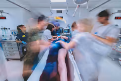 Hulpverleners rond een ziekenhuis bed. Foto lijkt bewogen om de hectiek aan te geven.