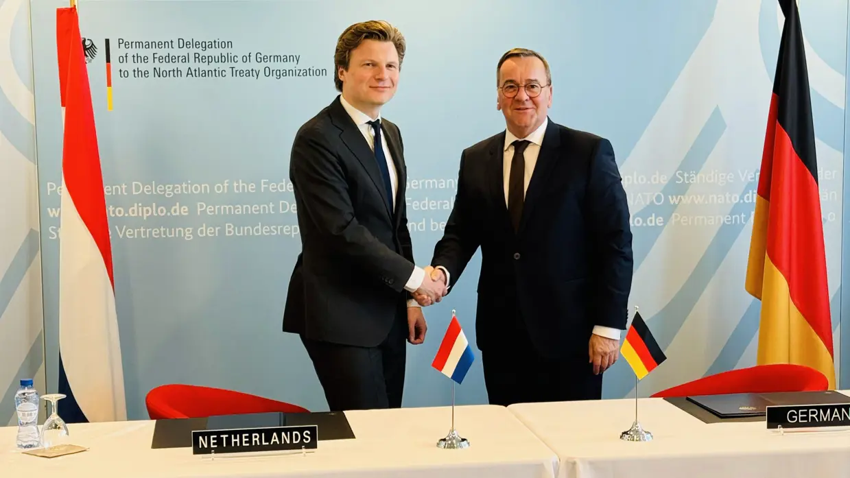 Defensieministers van Nederland en Duitsland schudden elkaar de hand.