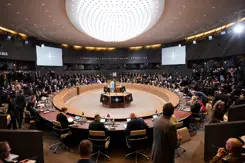 Defensieministers van de NAVO vergaderen aan een cirkelvormige tafel.