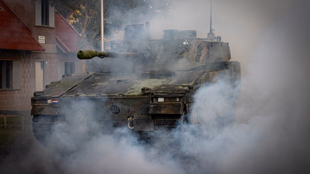 Een tank die door een rookgordijn heen rijdt.