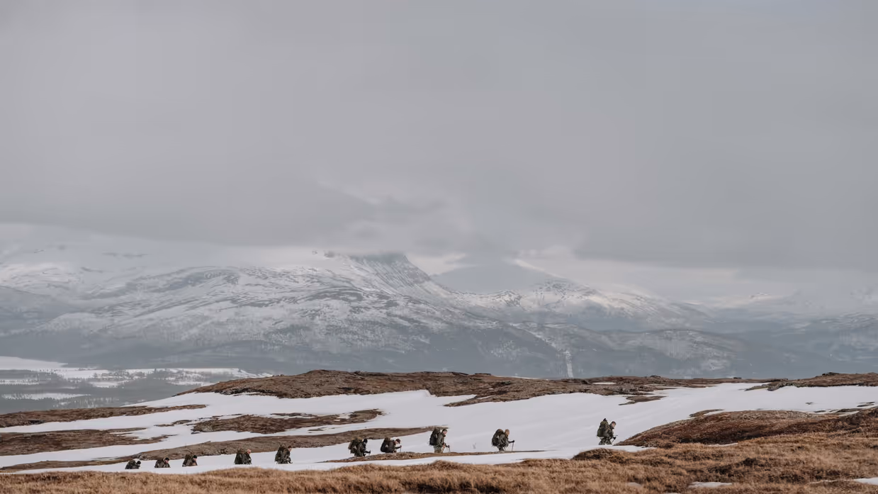 Een rij van soldaten loopt met bepakking over een toendra