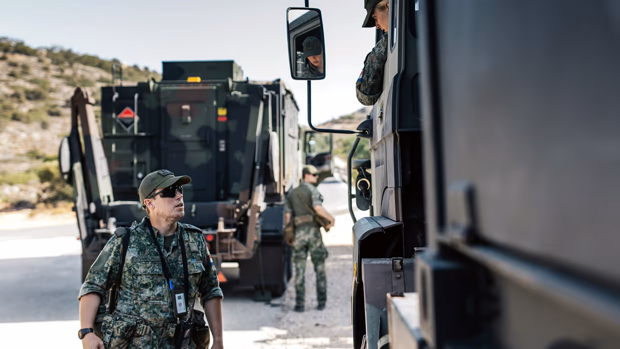 Een militair is in gesprek met een bestuurder in een konvooi.