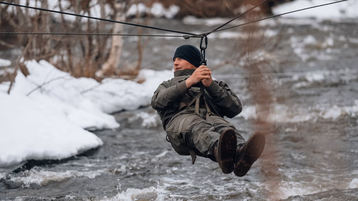 Een militair hangt aan een koord boven een rivier