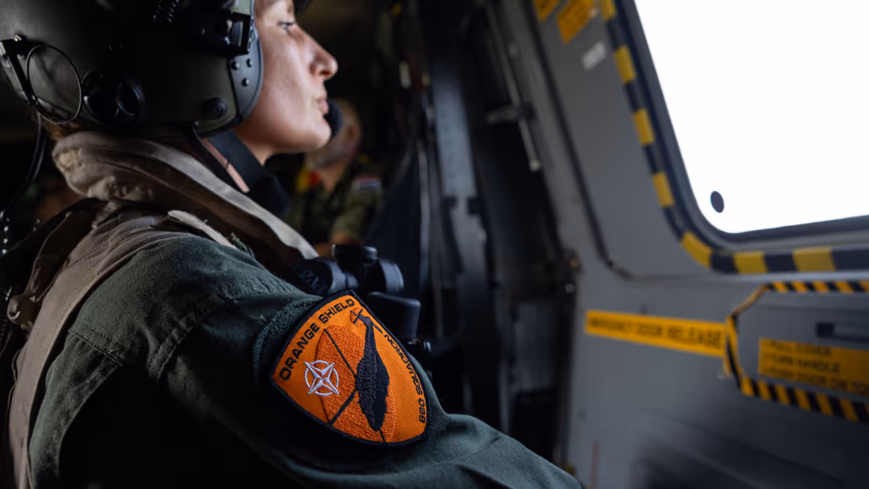 Militair met Orange Shield patch kijkt naar buiten.