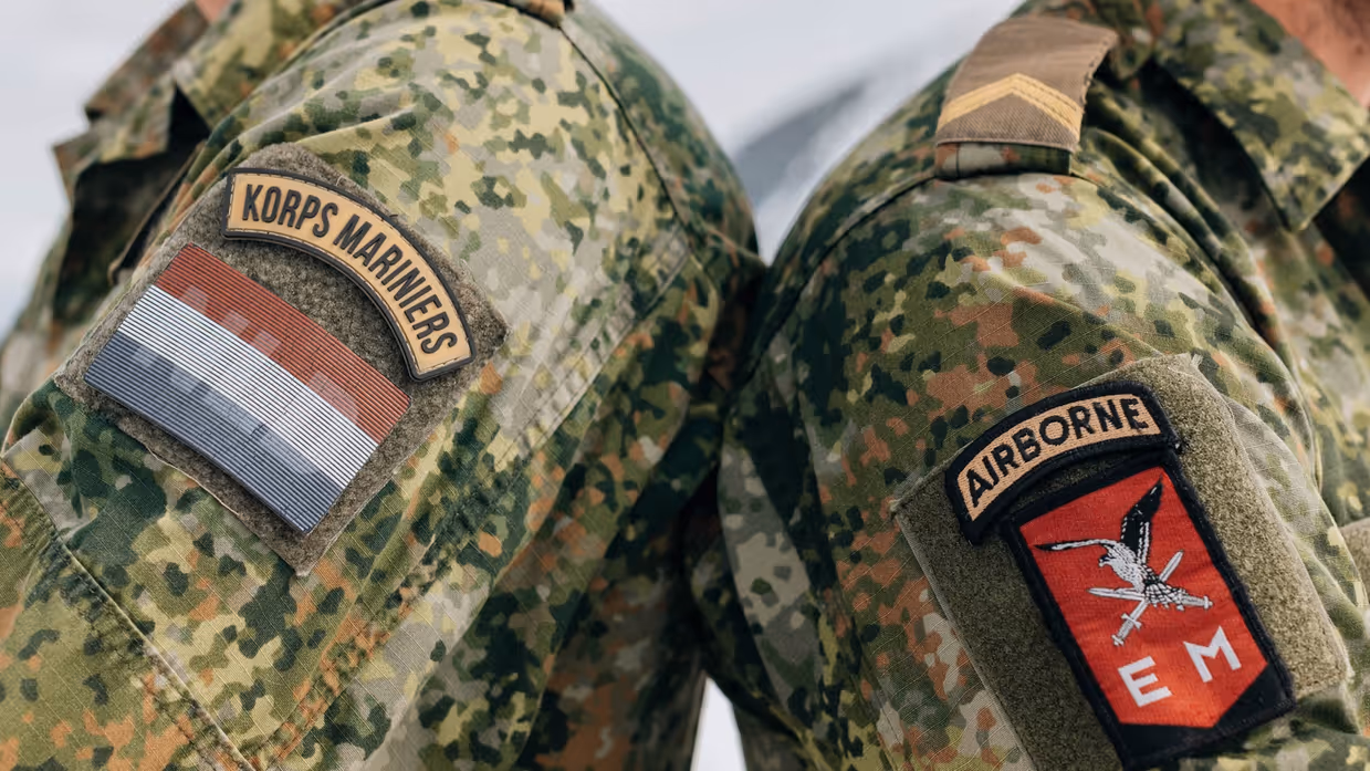 Twee militairen staan schouder aan schouder, de linker met een Korps Mariniers patch en de rechter met een 11 Luchtmobiele Brigade patch