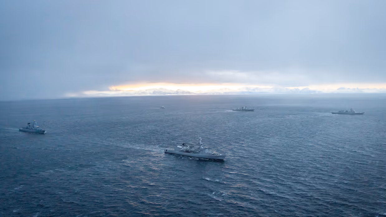 Militaire schepen varen rond op het water.