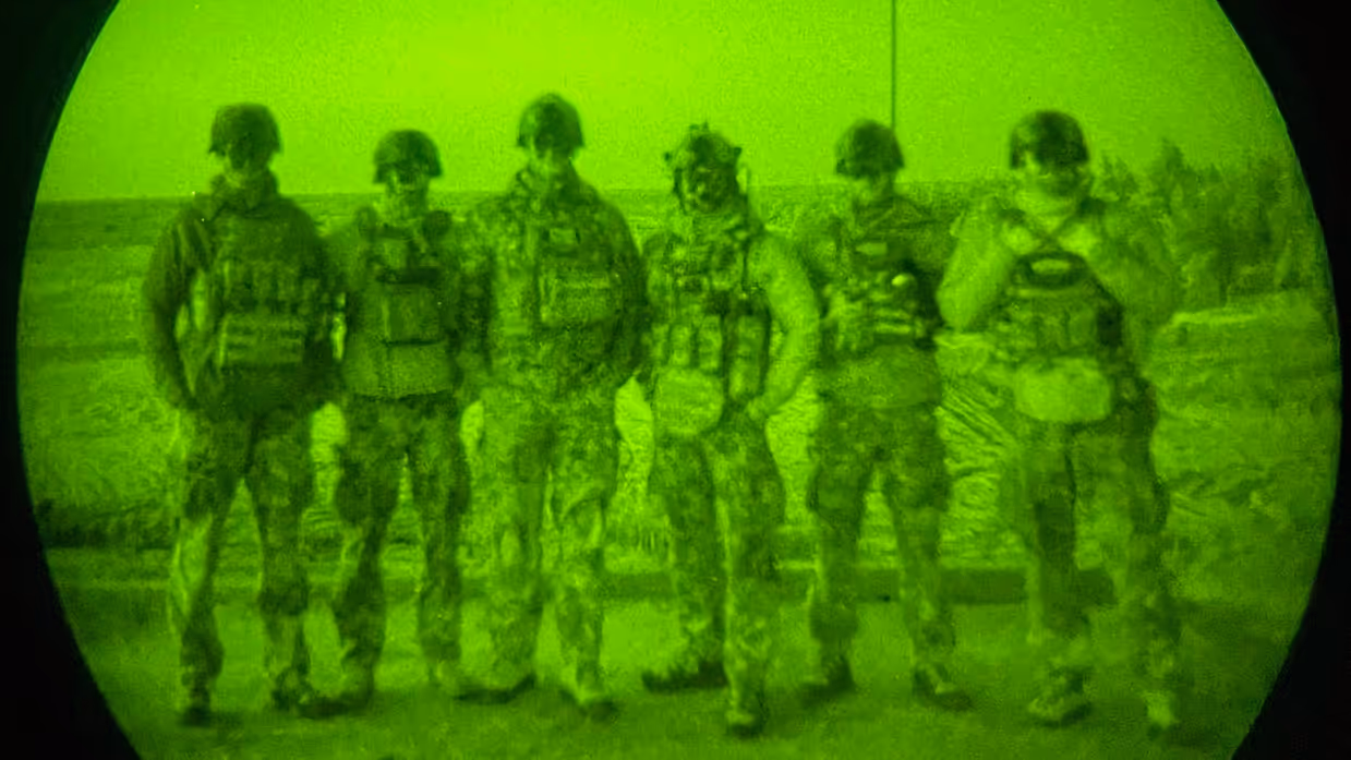 Een zestal militairen poseert samen voor een nachtlens.