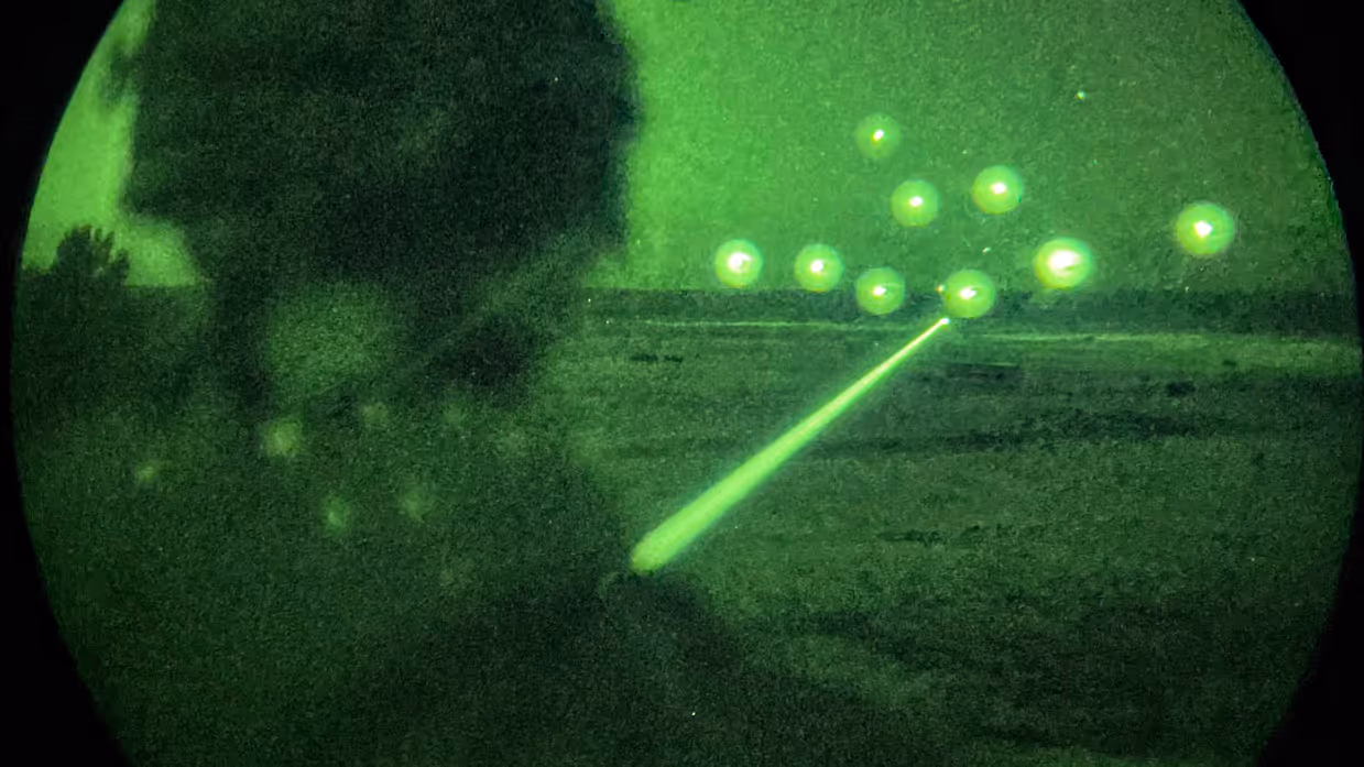 Een militair is zichtbaar van achteren met een speciale nachtlens, voor hem worden er flares afgeschoten.