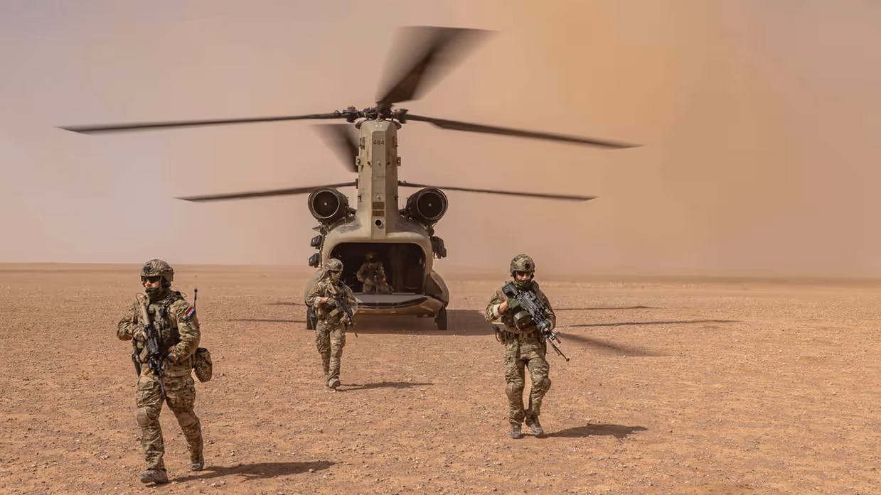 Bewapende militairen stappen uit Chinook-transporthelikopter.