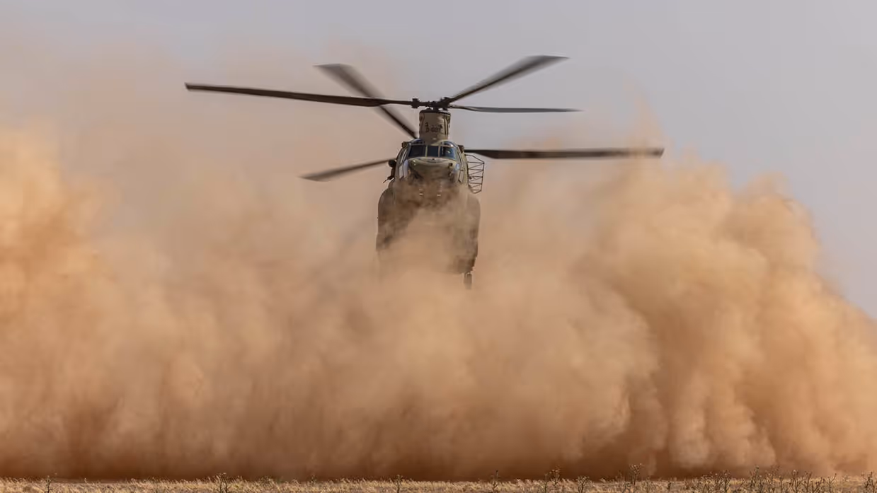 Chinook-transporthelikopter maakt stofwolk vlak boven de grond.