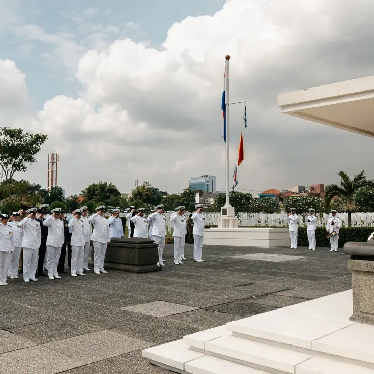 Militairen staan in tropentenue opgesteld op een militair ereveld in Soerabaja, op Java, en brengen de militaire groet. Op de andere foto staat de krans met opdruk Zr.Ms. De Ruyter die zij net hebben gelegd.