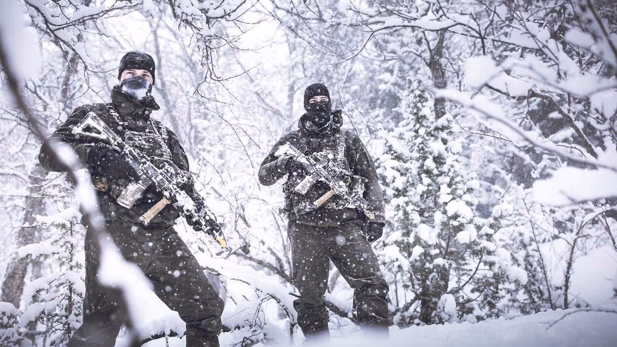 2  militairen in besneeuwd bos.