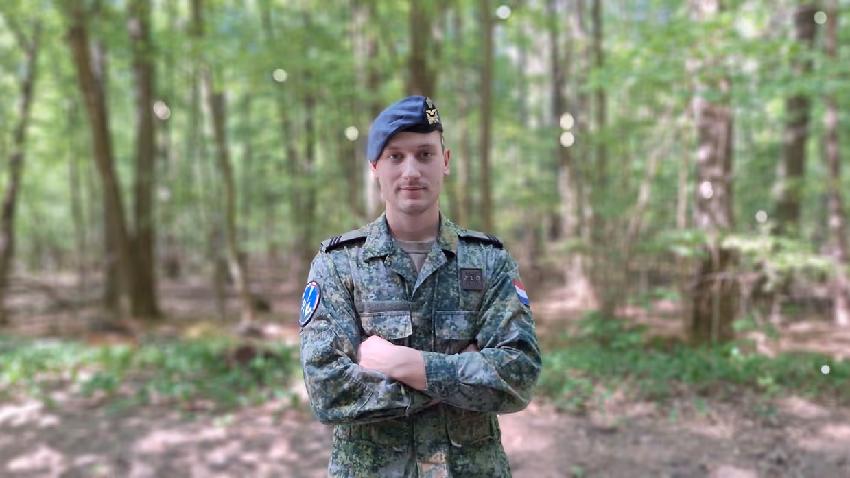 Sergeant Jorrin staat met armen over elkaar met een bos op de achtergrond. Foto: Defensie