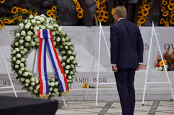 De koning staat voor de krans bij het monument. 
