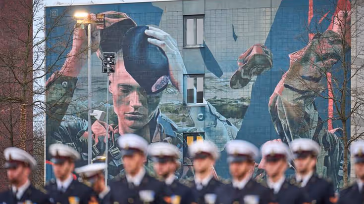 Militairen op een rij voor grote muurschildering.