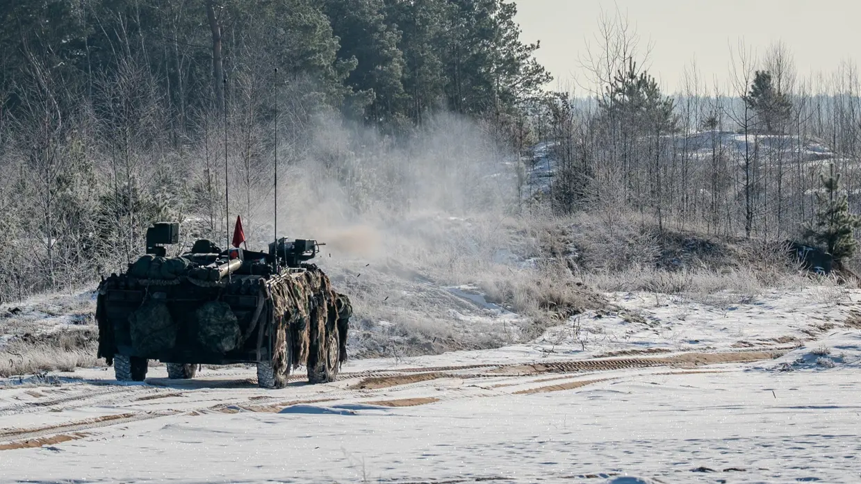 Militair voertuig rijdt door een besneeuwd landschap.