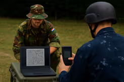 Twee militairen waarvan er een een qr-code scant. 