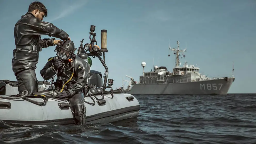 Militair in duikpak op rubberbootje maakt zich klaar voor duik in zee.