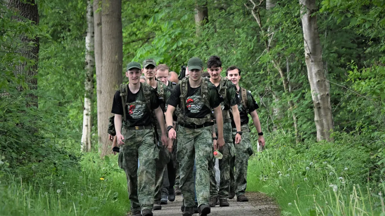 Militairen lopen over een pad door het bos. 