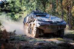Militair voertuig in bosrijke omgeving.