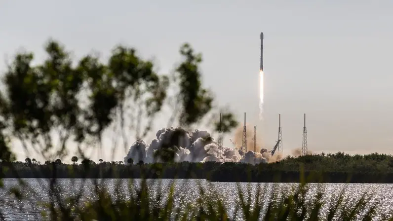 Een raket stijgt met veel rook en vuur op vanaf een lanceerplatform. 