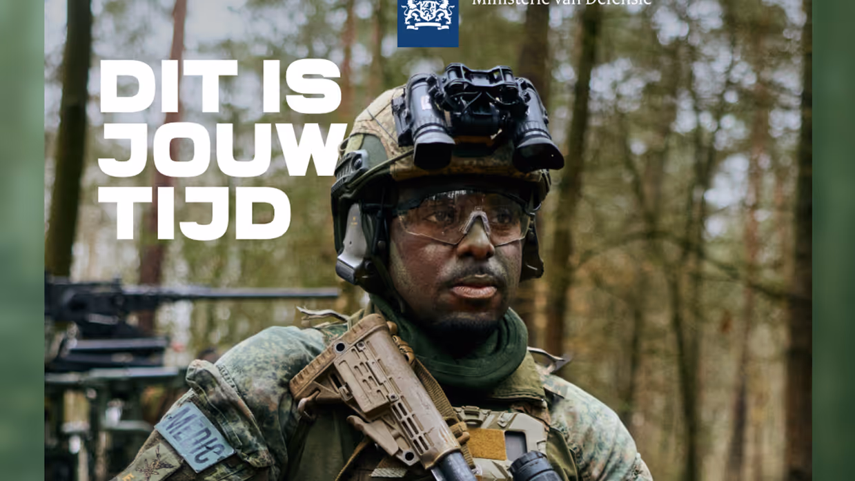 Een man in militaire kleding kijkt langs de camera.