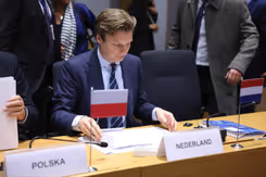 Minister Brekelmans tijdens vergadering achter naambordje van Nederland.