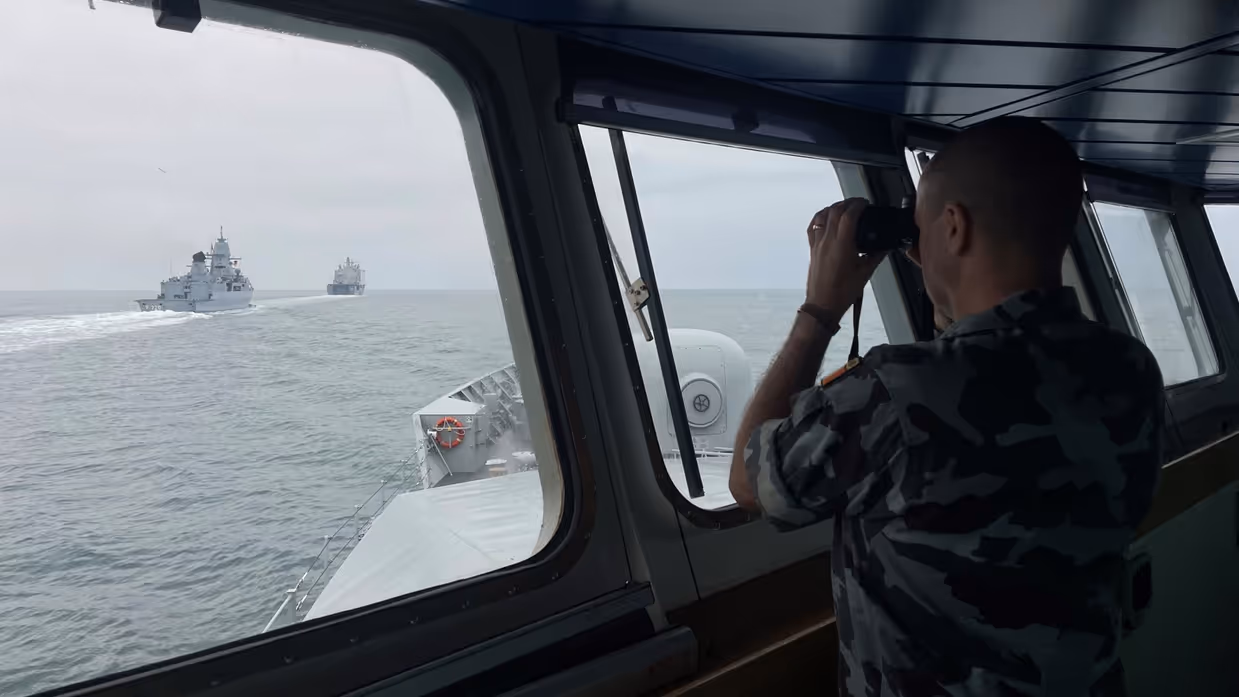 Een opvarende van het Ierse marineschip LE WIlliam Butler Yeats kijkt door een verrekijker naar de navigatieoefening..