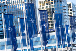 Rij vlaggen voor gebouw met NAVO-logo.